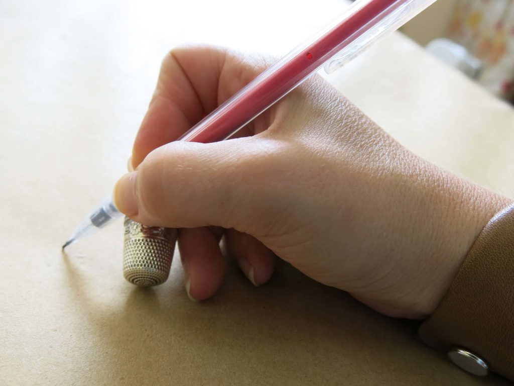 Comparing the hand position while holding a pencil to holding a needle using a thimble for hand sewing | Brooks Ann Camper Bridal Couture