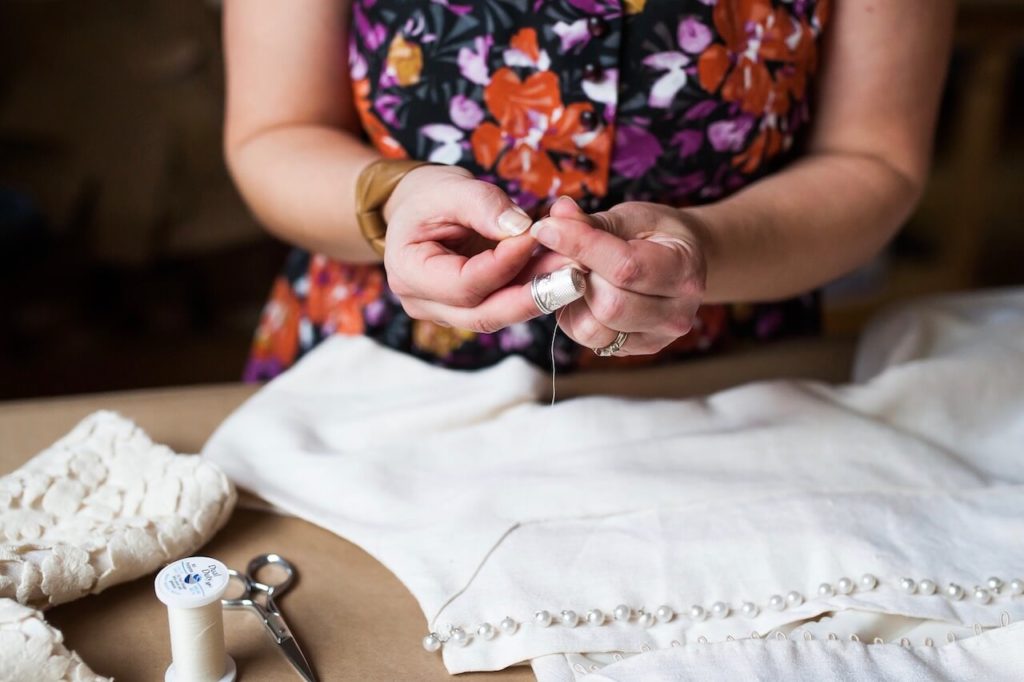 Brooks Ann hand sewing a wedding dress while using a thimble | Brooks Ann Camper Bridal Couture