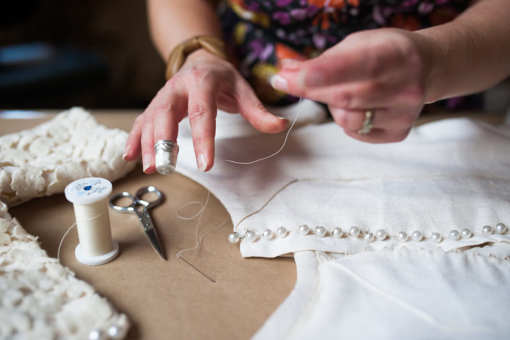 Brooks Ann hand sewing a wedding dress while using a thimble | Brooks Ann Camper Bridal Couture